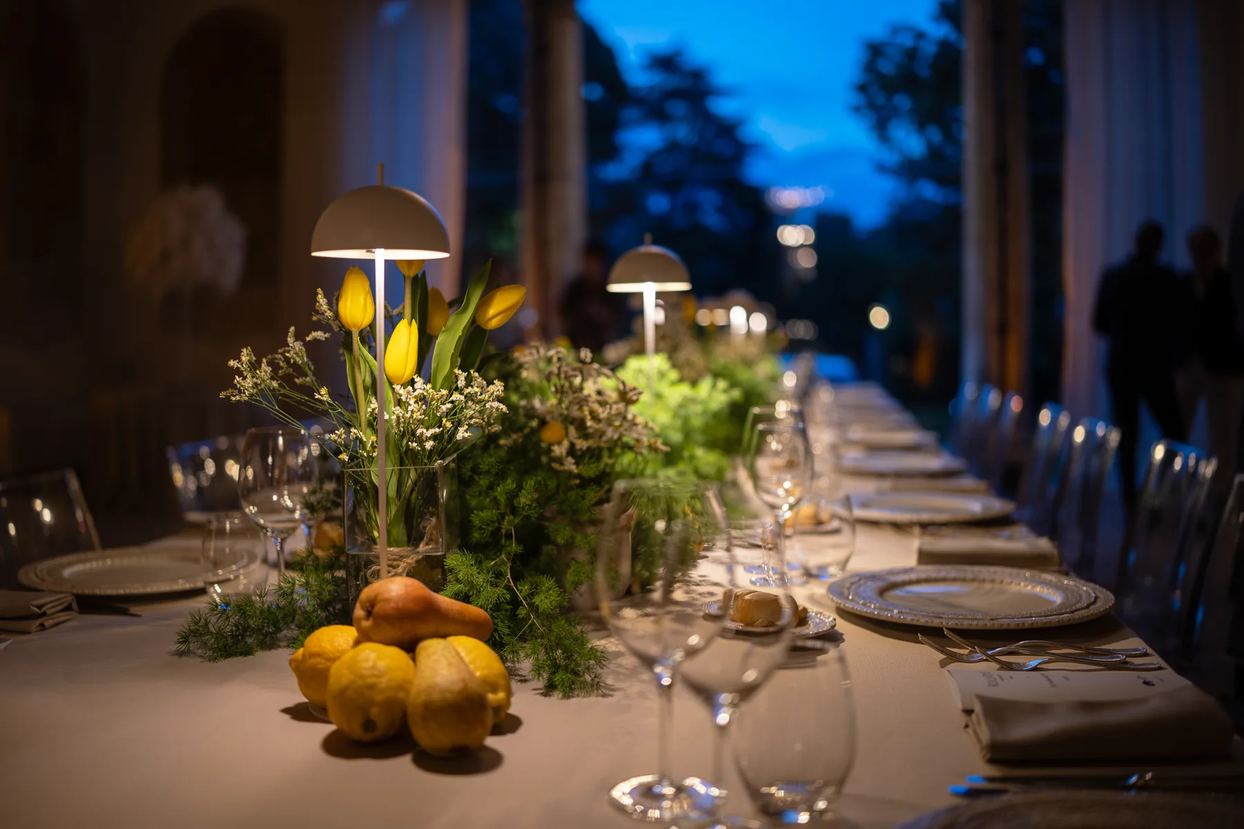 Tavola allestita nella loggia con fiori, candele e luce serale